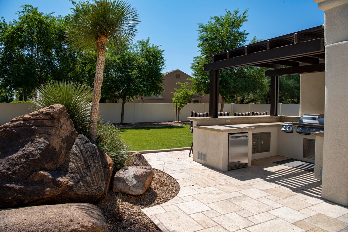 Outdoor kitchen with grill on a landscaped patio