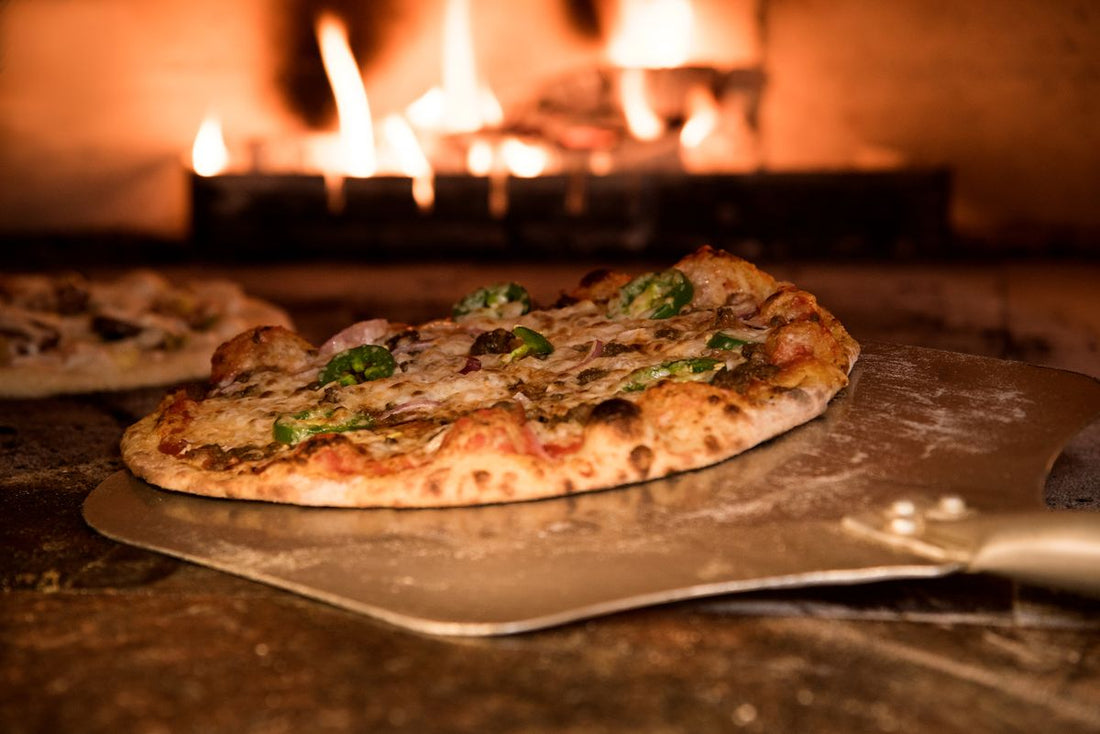 Pizza baking on a peel in a wood-fired oven
